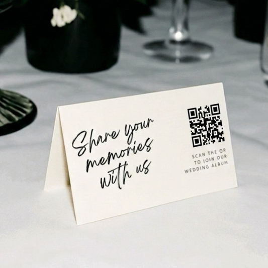 Table setting with a card inviting guests to share memories, accompanied by floral arrangements.